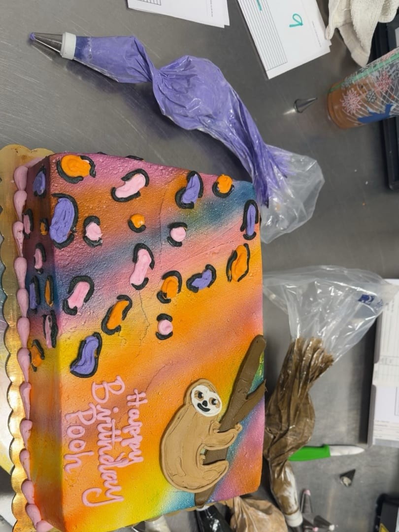 Rectangular birthday cake painted with a colorful leopard print and a sloth