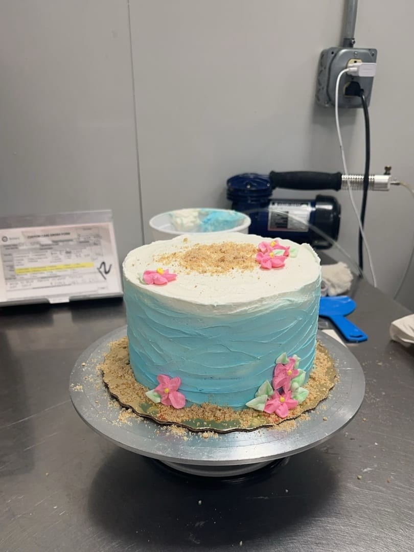 Light blue frosted cake with flowers on a cake stand