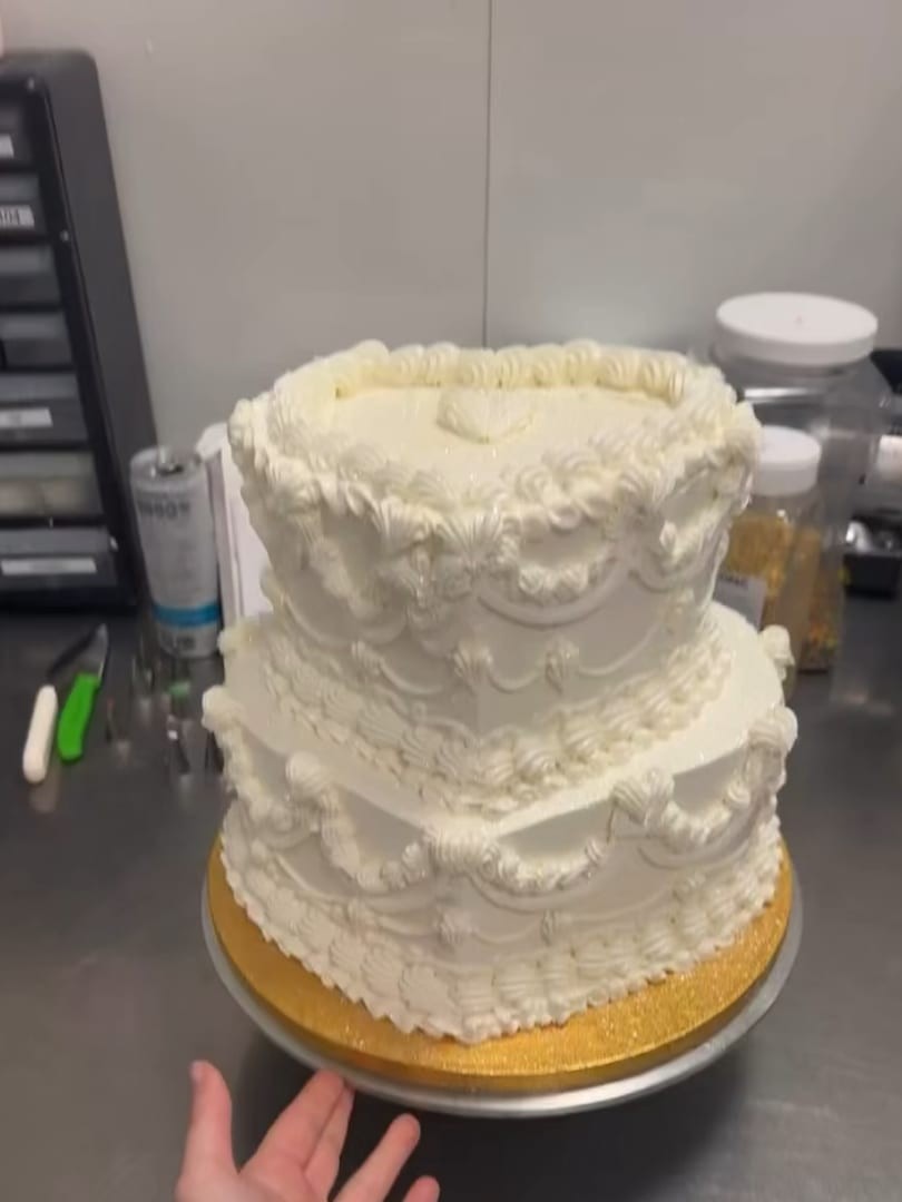 Two-tier white vintage-style cake with ruffled piping