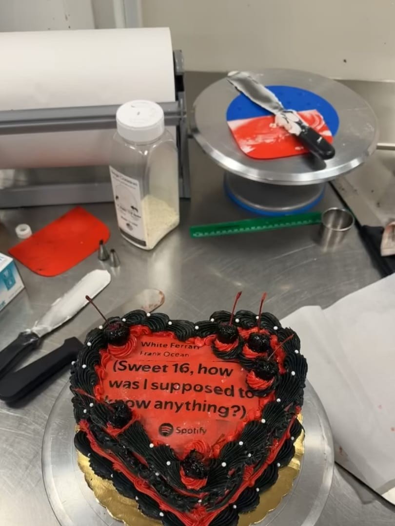 Red heart-shaped cake with a black piped border and lettering