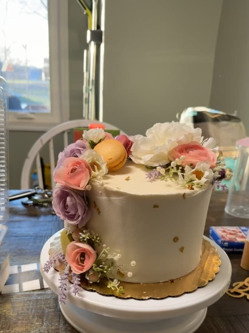 Tall cake with a cascade of blush flowers, macarons, and gold accents